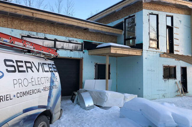 Camion de Services Pro-Électrique devant une maison en construction