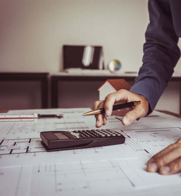 Homme regardant des plans techniques avec un crayon et calculatrice